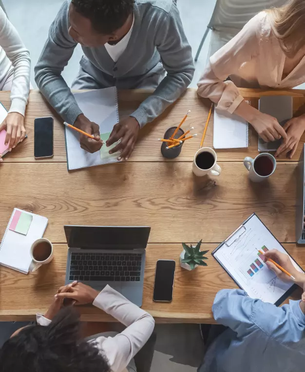 Birds eye view of a group of colleagues having a meeting on a wooden desk