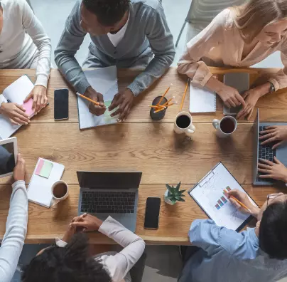 Birds eye view of a group of colleagues having a meeting on a wooden desk